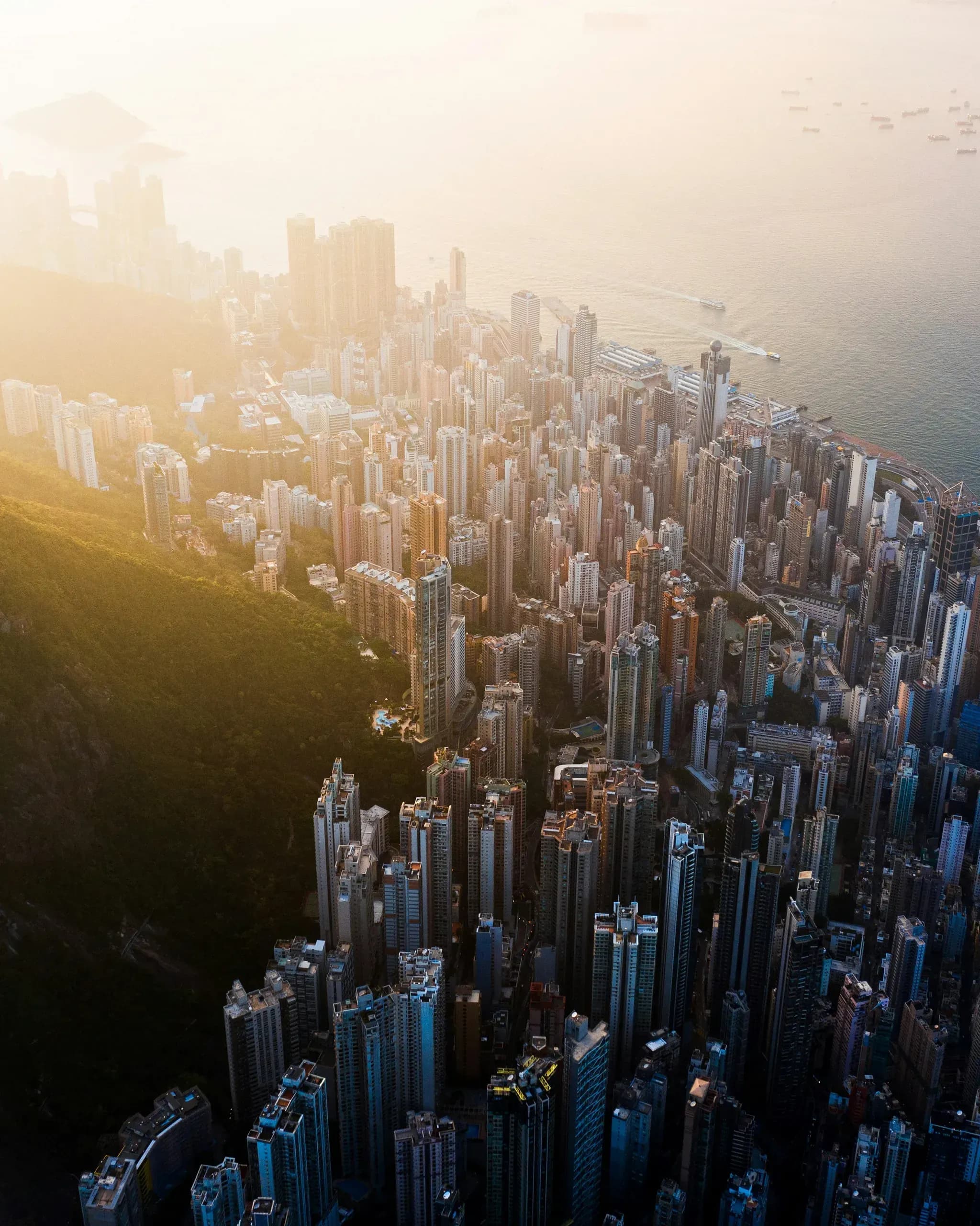 Aerial view of dense urban cityscape with tall buildings at sunset near waterfront
